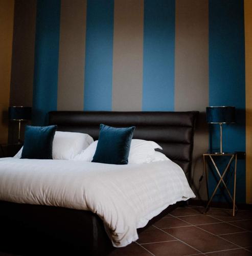 a bed with blue and white pillows in a room at Panoramic Villa Garassino - country rooms and fine restaurant in Treiso