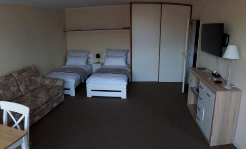 ガルミッシュ・パルテンキルヒェンにあるSunny 1-room apartment near railway stationのベッド2台とソファが備わるホテルルームです。