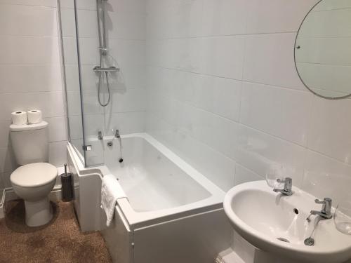 uma casa de banho com uma banheira, um WC e um lavatório. em The Waverley Hotel Maryport em Maryport