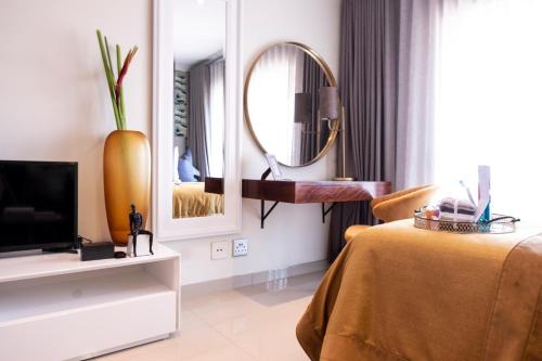 a room with a bed and a tv and a mirror at The Wilcrest Apartment in Randjesfontein