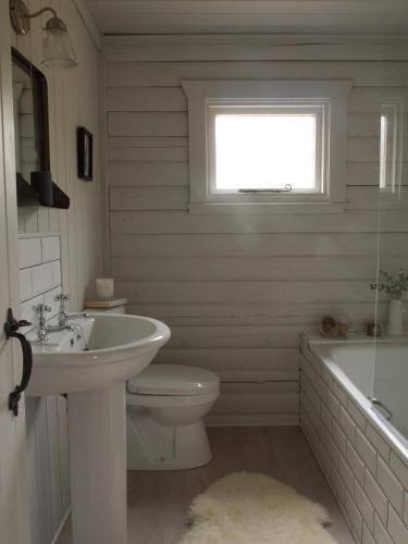 a bathroom with a sink and a toilet and a tub at Woodside Logcabin Ardoch Lodge in Strathyre