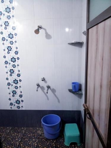 a bathroom with a toilet with a blue bucket at Hotel Rosary House in Malvan