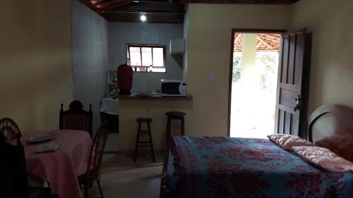 a bedroom with a bed and a table and a kitchen at Chalé em Ibitipoca in Conceição da Ibitipoca