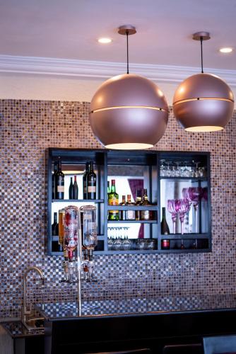 a bar with two pendant lights and a counter with wine glasses at The Ritzz Exclusive Guest House in Accra