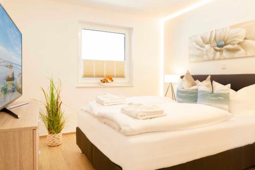 a white bedroom with a bed with towels on it at Haus Meeresleuchten mit Sauna- und Erlebnisbadnutzung in Ostseebad Sellin