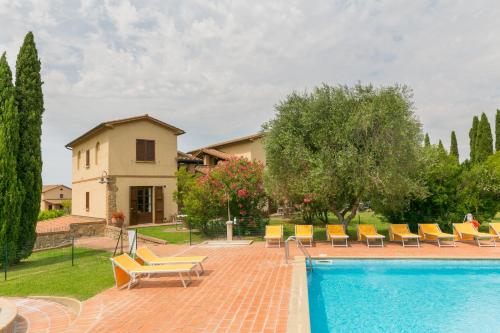 a swimming pool with chairs and a house at Relais La Pieve Vecchia in Riparbella