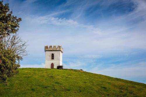 a white tower on top of a grassy hill at Coed Helen Holiday Park in Caernarfon