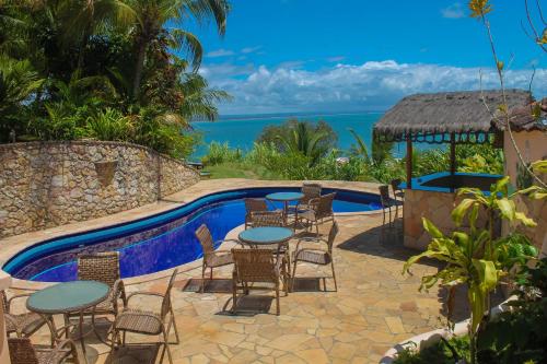 a patio with tables and chairs next to a pool at Pousada Colibri in Morro de São Paulo
