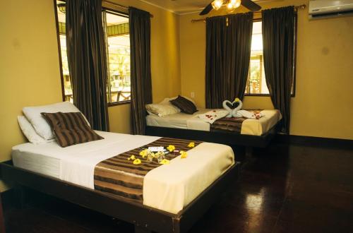 twee bedden in een hotelkamer met bloemen erop bij Overbridge River Resort in Paramaribo