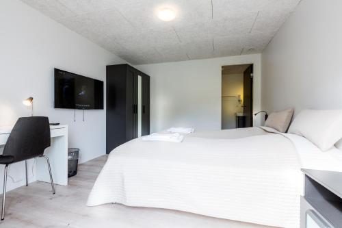 - une chambre blanche avec un grand lit blanc et un bureau dans l'établissement Gjaargardur Guesthouse Gjogv, à Við Gjógv