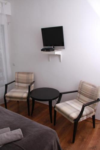 a living room with two chairs and a table and a tv at Sió Lodge in Siófok