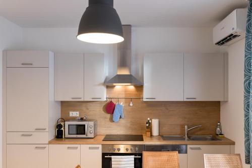 a kitchen with white cabinets and a sink and a microwave at Design-Apartments Graz in Graz