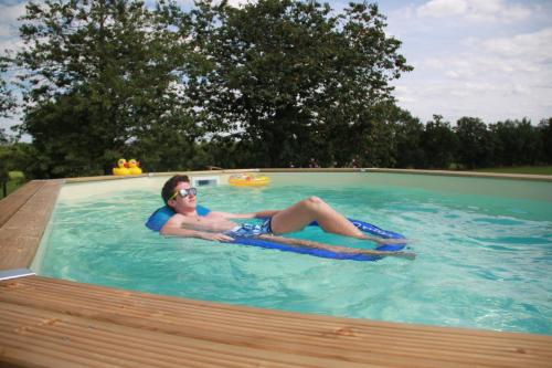 a man laying on a raft in a swimming pool at Auberge Le Romarin in Valgorge