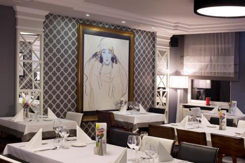 a restaurant with white tables and a painting on the wall at Miejsca noclegowe i Restauracja Kamiński in Kępno