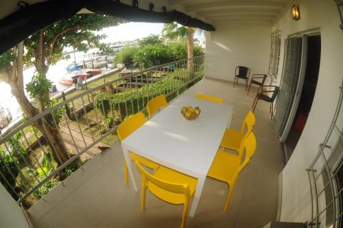 a white table and yellow chairs on a balcony at Lagoon Marina Apartments in Koolbaai