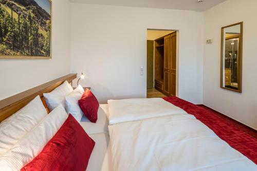 a bedroom with a white bed with red pillows at Hotel - Landgasthof Rebstock in Nimburg