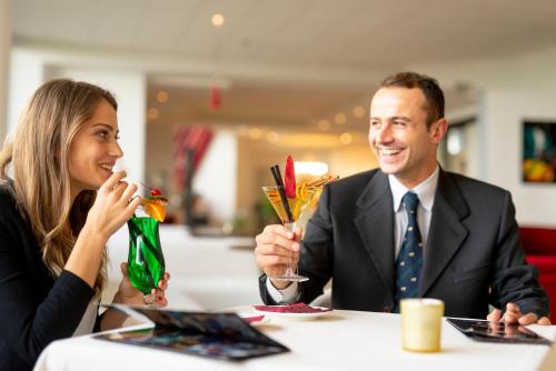 a man and woman sitting at a table with drinks at Grand Hotel Admiral Palace in Chianciano Terme