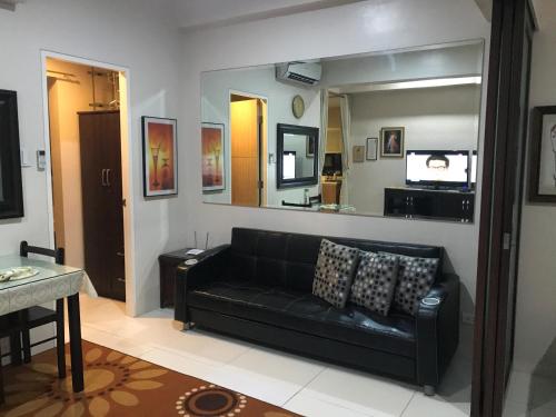 a living room with a black couch and a mirror at Creys condo at Pico de Loro Cove in Nasugbu