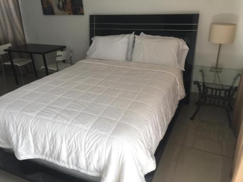 a bedroom with a large white bed and a table at Pelican By The Sea in Pompano Beach