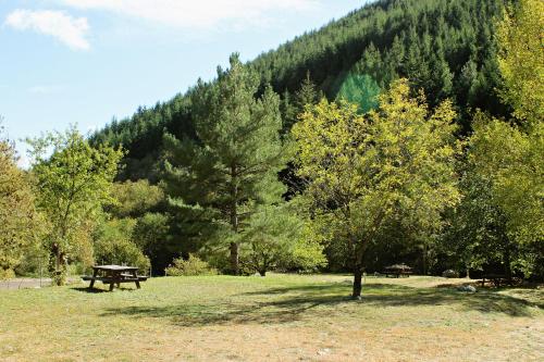 a park with a picnic table and trees in front of a mountain at Auberge Le Romarin in Valgorge