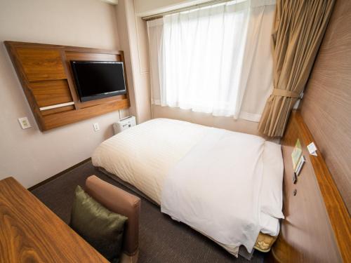 熊本市にあるNatural Hot Spring SUPER HOTEL Kumamoto Chamber of Commerceのベッドとテレビがあるホテルの部屋