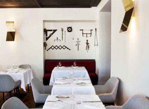 a restaurant with white tables and chairs and a wall with art at Relais de Chambord, a Small Luxury Hotels of the World in Chambord