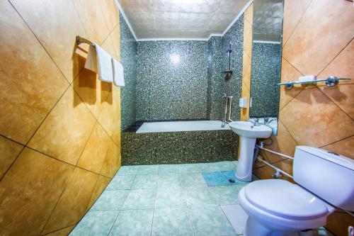a bathroom with a toilet and a sink and a tub at Rio Hotel in Khabarovsk