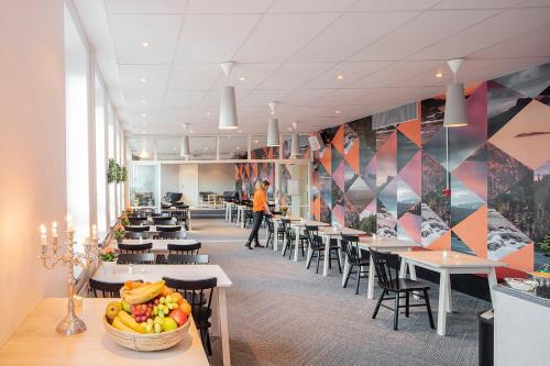 a cafeteria with tables and chairs and a bowl of fruit at Norrland YMCA Hostel Umeå in Umeå