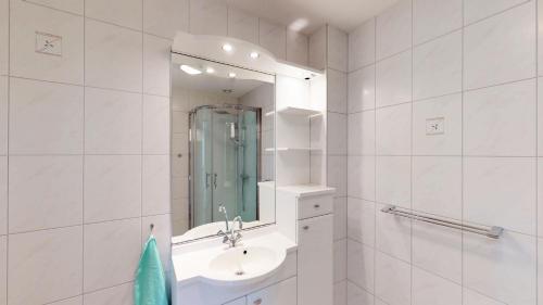 a white bathroom with a sink and a mirror at Villapark de Paardekreek in Kortgene