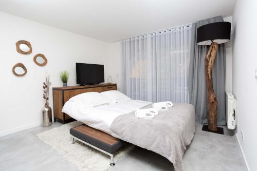 a white bedroom with a bed and a television at La Cordee 412 Apartment - Chamonix All Year in Chamonix-Mont-Blanc
