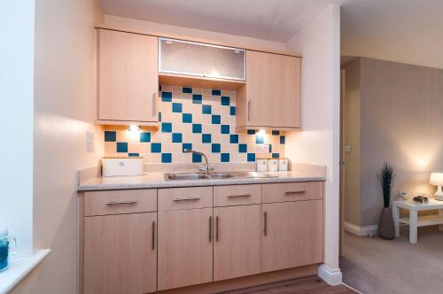 a kitchen with wooden cabinets and a sink at Central 2 bedroom apartment in Basingstoke