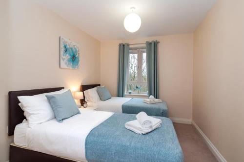 a bedroom with two beds and a window at Central 2 bedroom apartment in Basingstoke