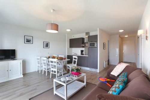 a living room and kitchen with a couch and a table at Résidence Néméa Les Balcons des Pêcheurs in Mimizan-Plage