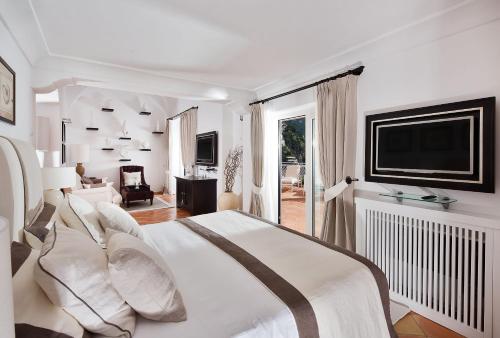a white bedroom with a large bed and a television at Covo Dei Saraceni in Positano