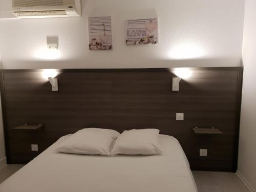 a bed in a room with two pillows on it at Hôtel Althea - Piscine et Sauna in Béziers