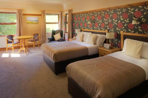 a hotel room with two beds and a table and chairs at Silver Tassie Hotel & Spa in Letterkenny