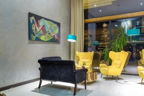 a lobby with yellow chairs and a painting on the wall at Hotel Berane in Berane