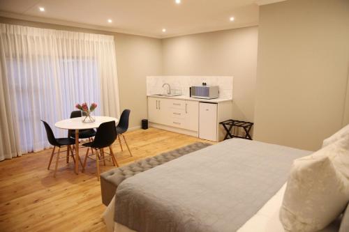 a bedroom with a bed and a table with chairs at Eden Guesthouse B&B in Dana Bay
