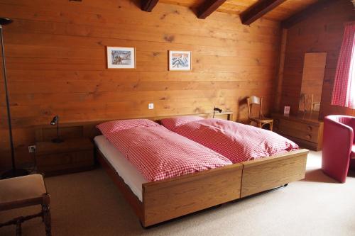 1 dormitorio con 1 cama en una habitación de madera en Hotel Simmental, en Boltigen