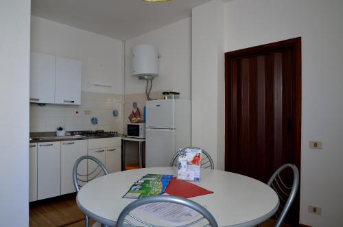 a kitchen with a table and chairs and a white refrigerator at Aurora Residence in Lido Adriano