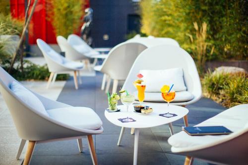 een groep stoelen en tafels met drankjes erop bij Hôtel Restaurant Athena Spa in Straatsburg