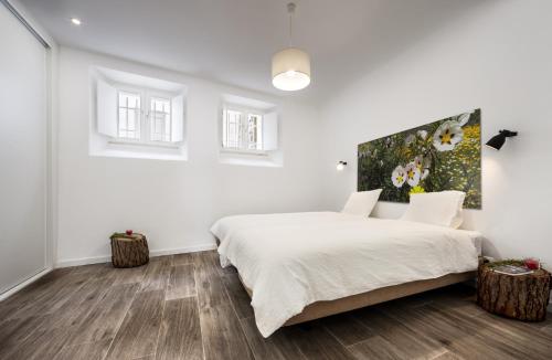 um quarto branco com uma cama grande e 2 janelas em Casa dos Apóstolos em Évora