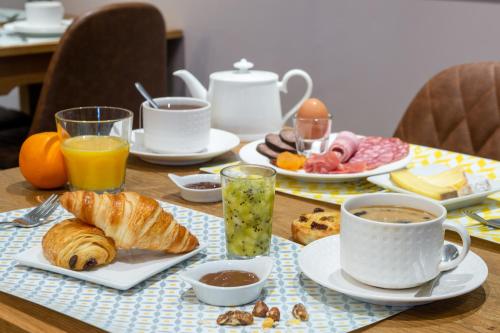 a table with a breakfast of coffee and croissants at Hôtel Traiteur Les Ormes, The Originals Relais in Barneville-Carteret