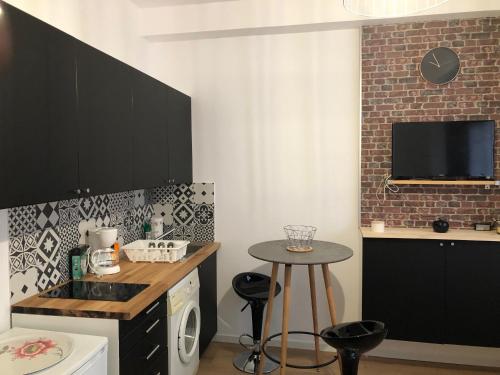 une cuisine avec des placards noirs et une table avec des tabourets dans l'établissement Marguerite, à Strasbourg