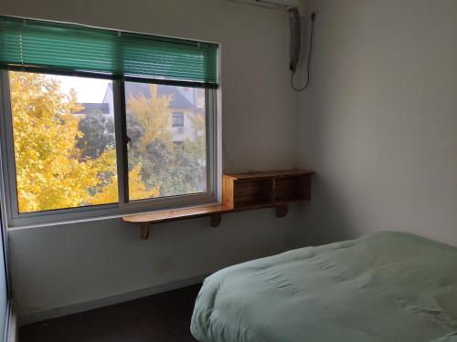 a bedroom with a bed and a window with green blinds at Suzhou Blue Gate Youth Hostel in Suzhou