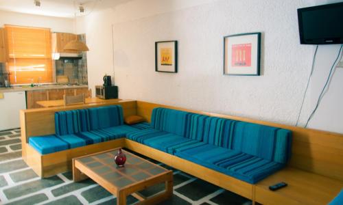 a living room with a blue couch and a table at Apollonia Hotel Apartments in Varkiza