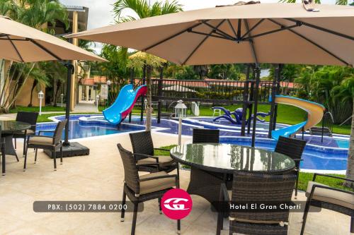 una piscina con mesas y sombrillas y un parque infantil en Hotel El Gran Chortí en Esquipulas