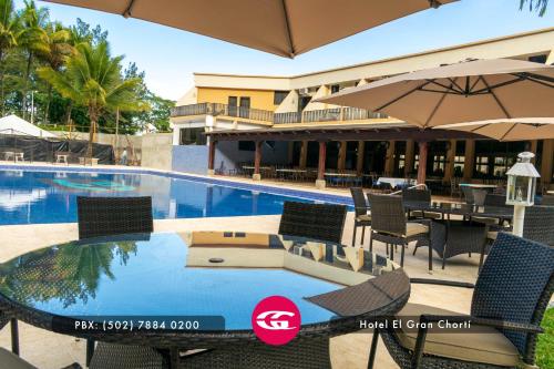 - une piscine avec une table, des chaises et un parasol dans l'établissement Hotel El Gran Chortí, à Esquipulas