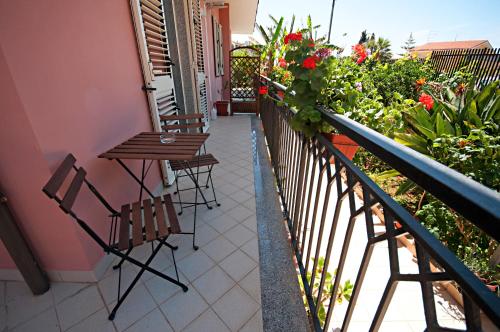 a balcony with two chairs and a table and flowers at Kosmos in Siracusa