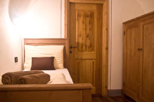 a bedroom with a bed with white sheets and a wooden door at Contrada Beltramelli in Villa di Tirano